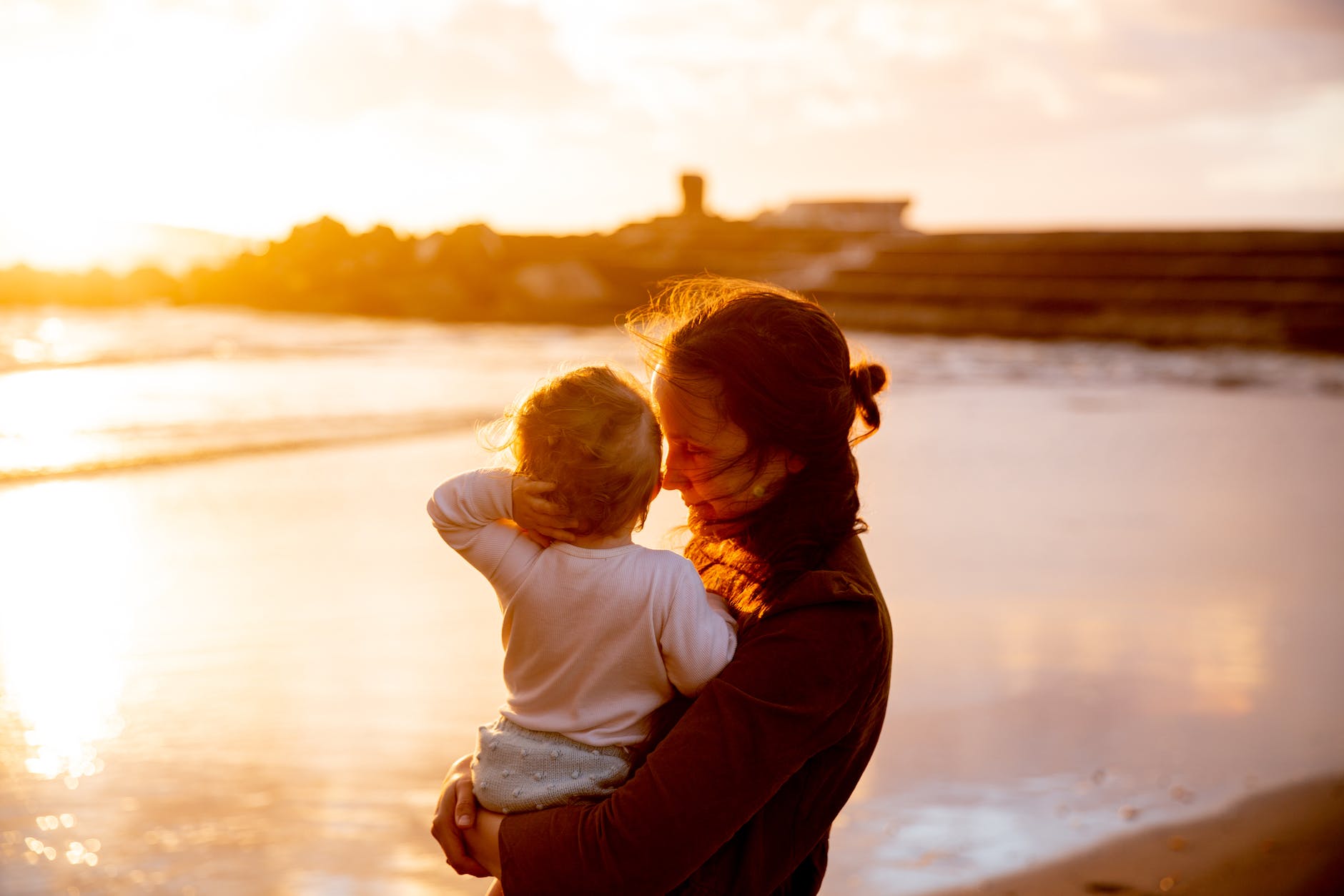 woman carrying baby in white shirt watching the sunset