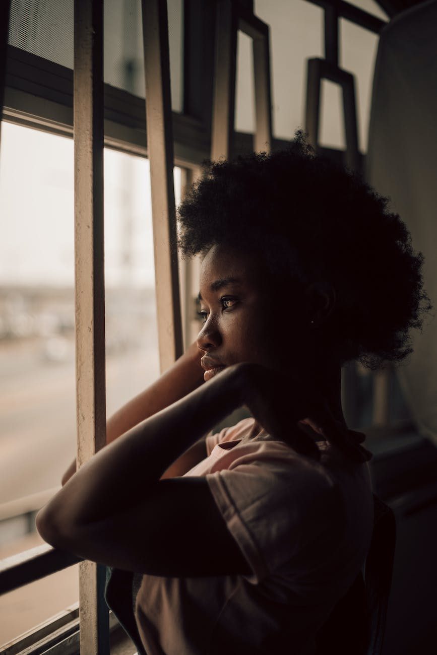 brown toned image of a woman looking through a window and contemplating